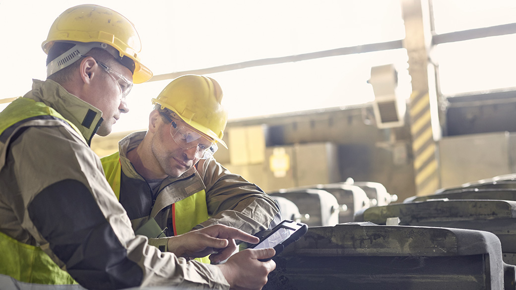 两位穿着正装的生意伙伴在仓库里查看一台平板电脑