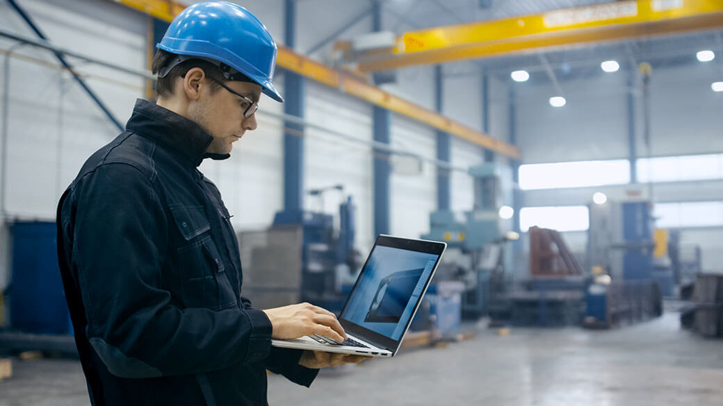 Factory worker using laptop with software
